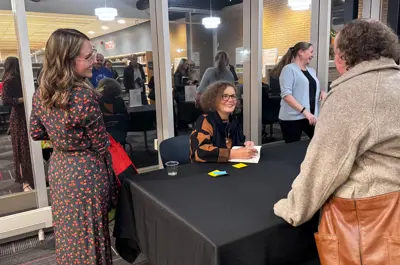 An author signing her book for a fan at the book signing table.